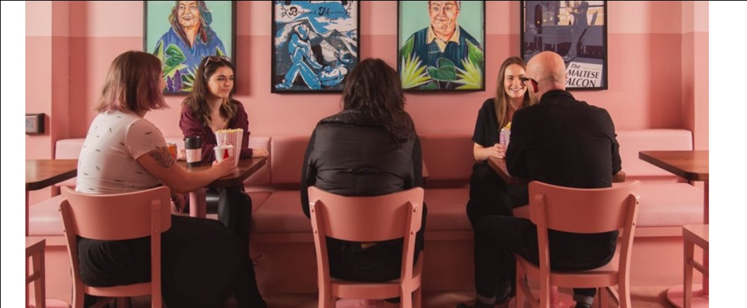 People gathered in a pink Calgary cafe space.